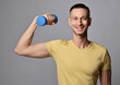 © Dmitry Lobanov - Cheerful young adult athletic man in yellow t-shirt works out with weights, holds a dumbbell in hand. Healthy vigorous lifestyle concept