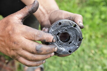 Wall Mural - Constant velocity ball tripod in serviceman hands with CV joint black grease, car gear repair outdoor