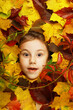 Artistic conceptual autumn girl portrait. Colorful leaves. Leaves of trees around an emotional face. Autumn is coming.