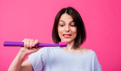 Wall Mural - Beautiful happy young woman with big toothbrush on blank pink background