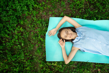 happy teenager is lying on grass on sunny summer day,girl is resting in park,young beautiful woman in nature is smiling,rejoicing,relaxing