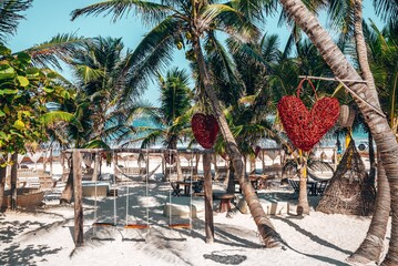 Empty swing with heart shape object hanging on coconut tree at a beautiful beach resort