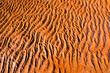 © Austockphoto - Detail shot of rippled wet bright orange sand
