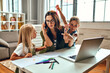 © Valerii Apetroaiei - A business woman and a mother are trying to work on a laptop when her little daughters are playing, fooling around and interfering with her. Freelance, work from home.