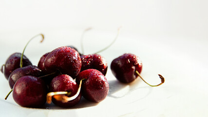 Wall Mural - juicy ripe cherries lie on a white table in the glare of light. copy space