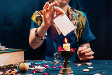 Poster - Divination and astrology. Witch holding an empty white tarot card and put to candles flame. Mock up. Copy space. Cartomancy and fortune telling concept