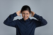 © fizkes - Head shot stubborn annoyed Indian woman plugging with fingers covering ears on grey studio background isolated, unhappy irritated businesswoman or student with closed eyes ignoring loud noise sound