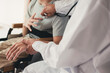 © GAYSORN - Hand of a kind docter checking heartbeat to asian handicapped teeager boy in examination room, People with disabilities activity in hospital or home for the disabled or quarantine, Healthcare concept.
