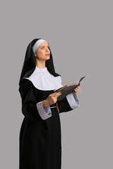 Wall Mural - Young nun with Bible on grey background