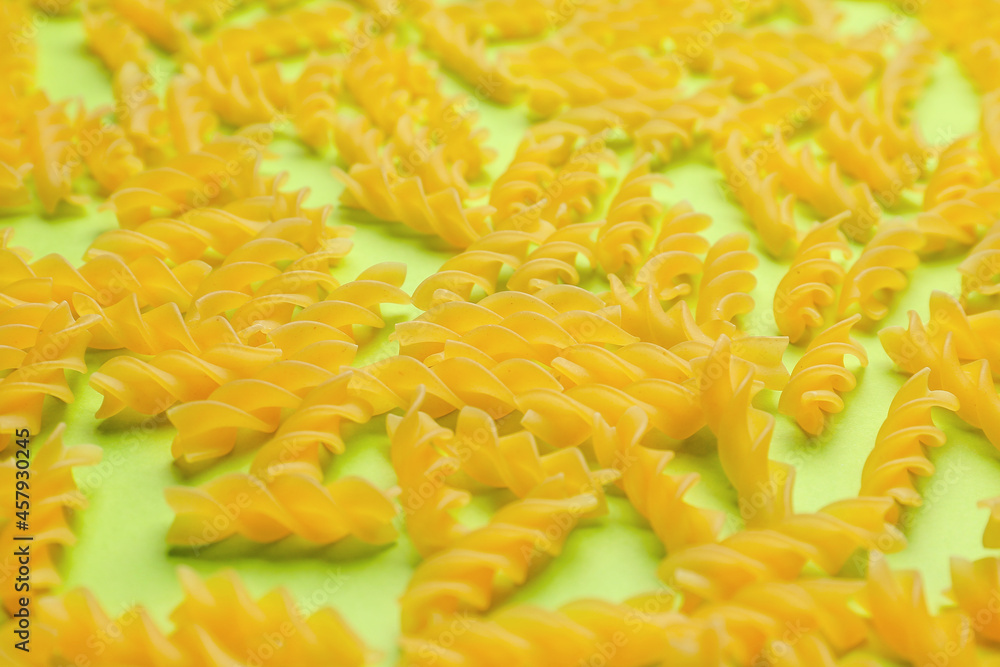 Uncooked fusilli pasta on color background