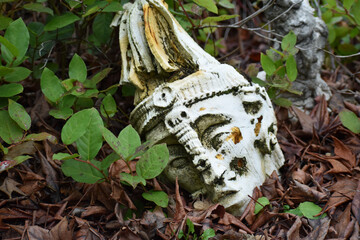 Poster - Closeup of an old stone statue covered in mosses on the ground in a park