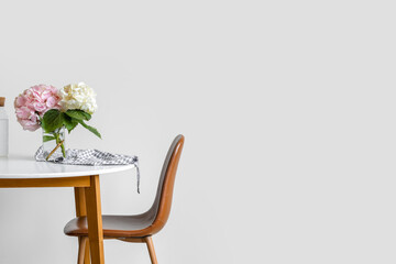 Wall Mural - Vase with hydrangea flowers on table near light wall