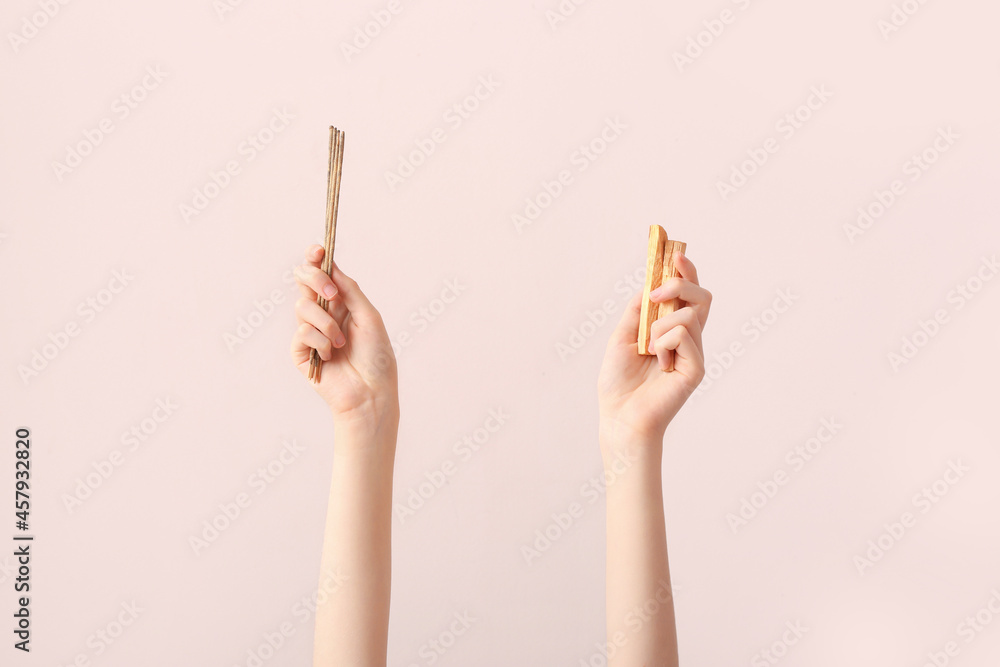 Hands with Palo Santo and  incense sticks on color background