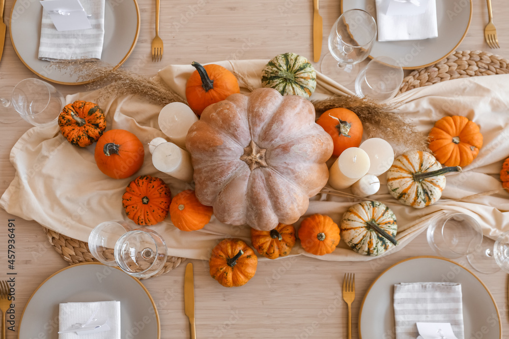 Beautiful autumn table setting with pumpkins and candles in room