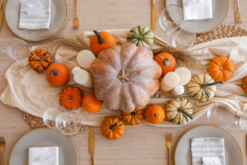 Beautiful autumn table setting with pumpkins and candles in room