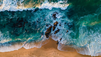 turquoise water with wave with sand beach background rocks and corals from aerial top view in sunset