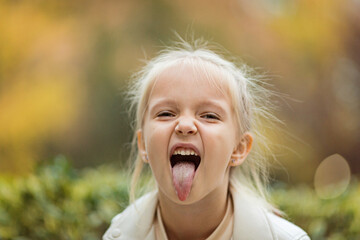 Cute stylish little girl with long blonde hair walking in autumn park. Autumn kids fashion. Happy childhood. Lifestyle portrait. Caucasian child 6 years old outdoor