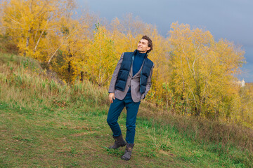 Tall handsome man outdoor in autumn forest on the hill