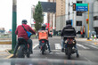 Food delivery driver with backpack on a motorcycle riding along a street.