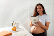 © satura_ - Pregnant woman using digital tablet. Breakfast time. Technology and pregnancy concept.