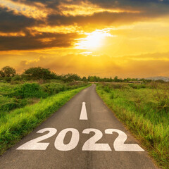 Empty asphalt road and New year 2022 concept. Driving on an empty road to Goals 2022 with sunset.