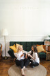 © diignat - Beautiful young woman and adult girl are drinking tea, talking and smiling while sitting on floor at modern home