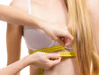 Woman measuring girl under breast
