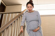 A young pregnant Asian woman going down the stairs carefully