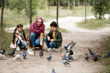 Muslim Family Feeding Doves In Park