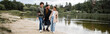 © LIGHTFIELD STUDIOS - Smiling arabian man hugging kids near lake in park, banner