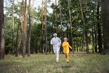 Canvas Print - Arabian parent and son running together in park