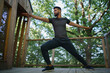© Halfpoint - Low angle view of happy young man doing exercise outdoors on terrace of tree house, weekend away and digital detox concept.