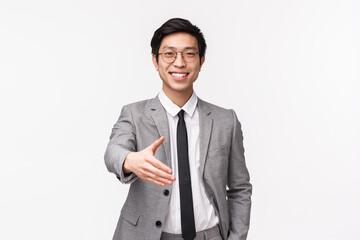 Waist-up portrait of friendly confident, successful asian businessman stretching hand forward for handshake with business partner, nice to meet you, formal greeting, white background