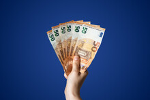 Hand Holding Three Hundred Euros In 50 Euro Bills With Blue Background