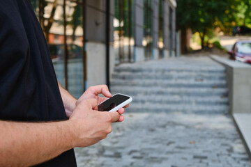 Wall Mural - a man with a smartphone in his hands stands near the business center. a businessman is sending a tex