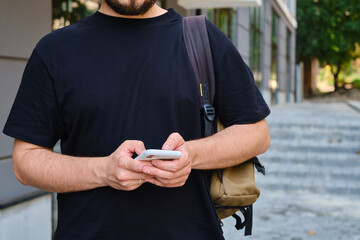 Wall Mural - a man with a smartphone in his hands stands near the business center. a businessman is sending a tex