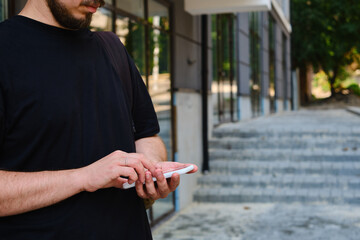 Wall Mural - a man with a smartphone in his hands stands near the business center. a businessman is sending a tex