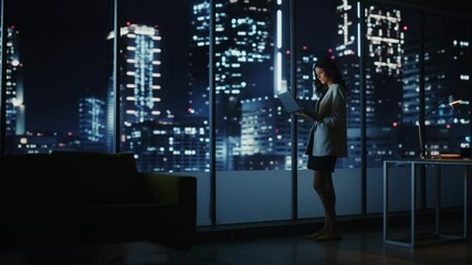 Poster - Big City Modern Office at Night: Ambitious Successful Businesswoman Standing and Using Laptop. Beautiful Female Digital Entrepreneur Thinking of Investment Strategy for e-Commerce Project