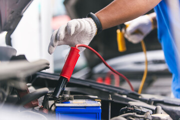 Wall Mural - Close up of hand Charging car battery with electricity trough jumper cables, copy space for text.