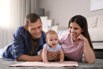 Wall Mural - Happy family with their cute baby on floor at home