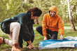 © Syda Productions - camping, tourism and travel concept - happy couple setting up tent outdoors