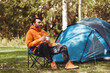 © Syda Productions - camping, tourism and travel concept - happy man drinking tea at tent camp