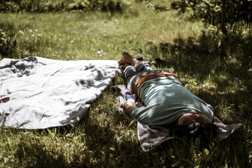 A man sleeping on a blanket in a shadow. Man asleep in grass. Man taking a nap on warm summer day. 