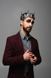 distrustful man in vampire king halloween crown looking at camera isolated on grey