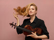 © rubchikova - Beautiful woman with red violin isolated on pink background
