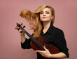 © rubchikova - Beautiful woman with red violin isolated on pink background