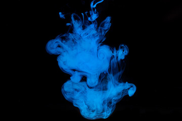 Blue paint dissolves in water on a black background. Watercolor paint in water