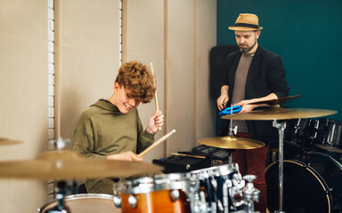the teacher conducts a drumming lesson for a teen boy.