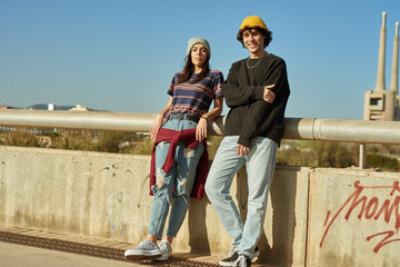 Young couple looking at you outdoors