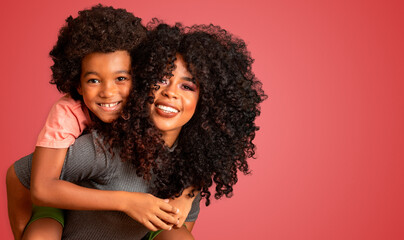 Portrait of young African American mother with toddler son. Red background. Brazilian family.